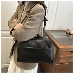 Close-up of a black PU leather shoulder bag with sleek silver zipper and front pocket detail