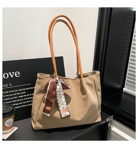 Close-up of khaki tote bag with textured finish and decorative silk scarf detail