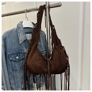 Detail of dark brown suede hobo bag featuring long hanging fringes and a bohemian style