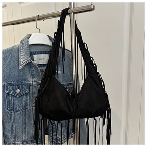 Detail of black suede hobo bag featuring bohemian tassels and a minimalist crescent shape