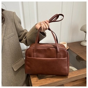 Detail of vintage brown PU leather handbag featuring a large front pocket and slim strap