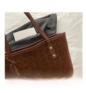 Detail of leopard print tote bag with metallic rivet and suede texture in warm light