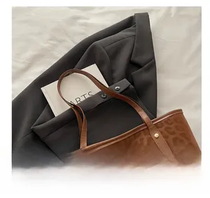 Top view of large leopard print tote bag with leather straps on white fabric background
