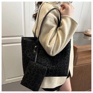 Detail of leopard print tote bag with matching pouch and black leather straps on model