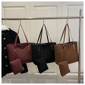 Three-color leopard print tote bags with matching pouches hanging on a stainless steel rack