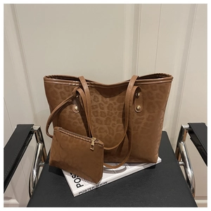 Detail of leopard print tote bag and small matching pouch on a black leather chair