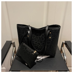 Detail of leopard print tote bag and pouch set on a stylish black chair with gold hardware