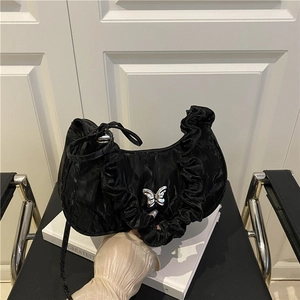 Elegante borsa a mezzaluna nera a pieghe con farfalla d'argento su sedia di pelle