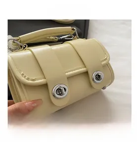 Détail du sac en cuir crème avec doubles verrous rotatifs en métal argenté et structure multicouche