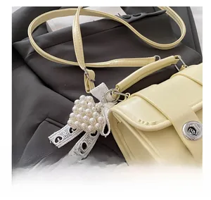 Détail du mini sac jaune avec breloque cœur en perles et nœud décoratif en dentelle