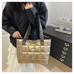 Detail of golden quilted space cotton tote bag with ethnic pattern strap on model