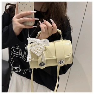 Détail du sac à main crème avec fermoirs argentés, cœur en perles et nœud en dentelle