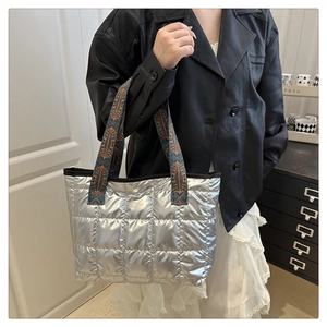 Detail of silver quilted tote bag with retro geometric pattern straps and metallic finish