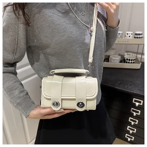 Mini sac polochon crème avec boucle argentée et bandoulière porté par un mannequin
