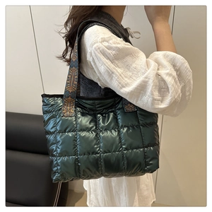 Detail view of dark green quilted tote bag with ethnic pattern webbed strap