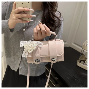 Détail du sac boston rose avec breloque nœud perlé et fermoir rotatif en argent