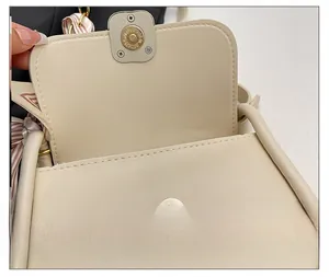 Detailed macro view of the magnetic snap closure on a cream vegan leather crossbody bag