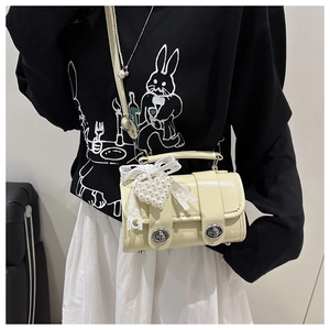Détail du sac crème avec nœud en dentelle et décoration de pendentif cœur en perle