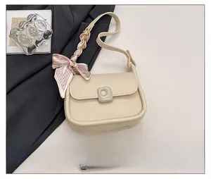 Detail view of a beige shoulder bag with a striped silk scarf and phone size reference