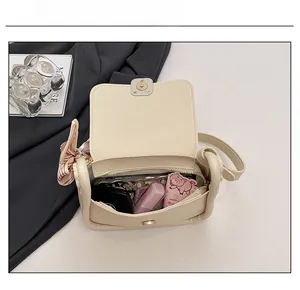 Detailed interior of a cream shoulder bag showing main compartment and front pocket