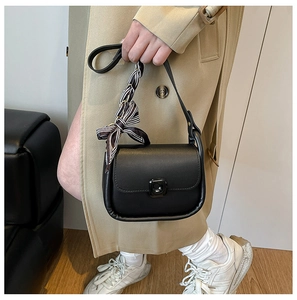 Detail of a black leather square crossbody bag with silk scarf on the shoulder strap