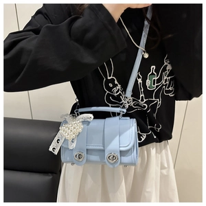 Detalle del bolso de cuero brillante azul claro con colgante de perlas y cierre de plata