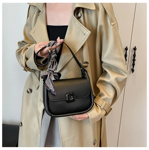 Detail of black leather underarm bag with striped silk scarf tied on the shoulder strap