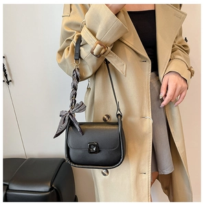 Detail of a black leather crossbody bag featuring a chic black and white striped scarf