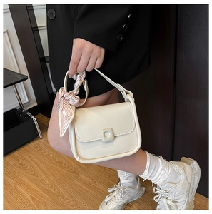 Close-up of cream square handbag with decorative pink striped silk scarf on the handle
