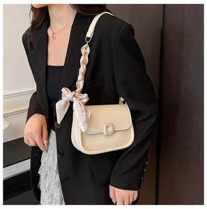 Detail of cream crossbody bag with silk scarf wrapped handle and bow decoration