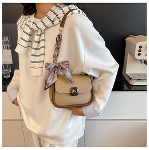 Detail of crossbody bag with silk scarf wrapped strap and brown magnetic lock closure