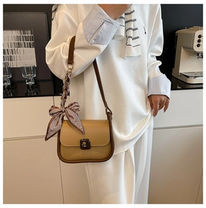 Close-up of khaki and brown leather crossbody bag with striped silk scarf detail