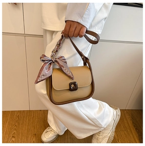 Detail of khaki square crossbody bag with silk scarf handle and resin buckle closure