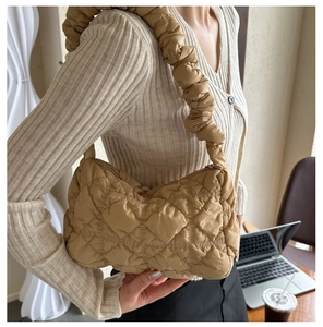 Detail of khaki quilted shoulder bag with bubble pleated strap in a casual office setting
