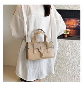 Détail du sac à main beige avec rabat à paillettes et fermoir doré sur modèle