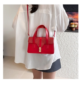 Détail du sac rouge pailleté avec fermoir rotatif doré et bandoulière réglable pratique