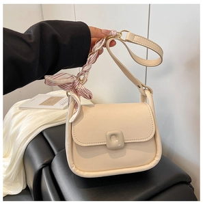 Detail of cream crossbody bag with silky pink striped scarf tied on the handle