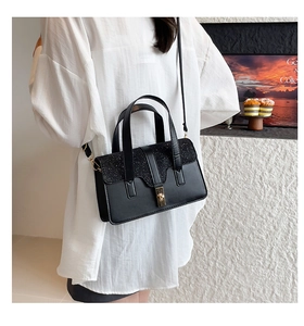 Détail du sac à main noir à paillettes avec fermoir doré porté par un mannequin en tenue