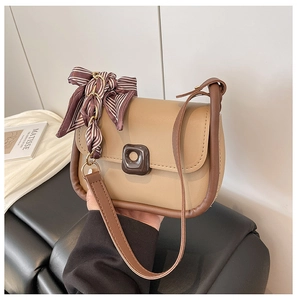 Close-up of khaki crossbody bag with brown trim and striped silk scarf detail