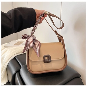 Detail of beige faux leather handbag with brown trim and silk scarf wrapped handle