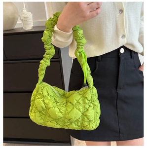 Detail of light green quilted puffy bag with ruffled handle and zip closure