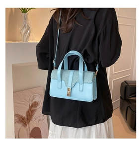 Detail of light blue crossbody bag with glitter flap and gold twist lock on model