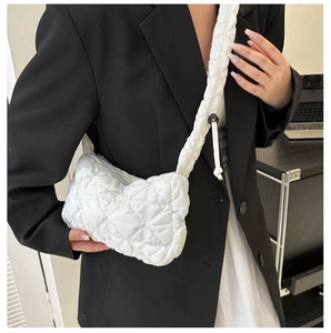 Detail of white quilted puffy crossbody bag showing texture and adjustable strap