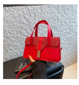 Detail der roten Glitzer-Handtasche mit goldenem Drehverschluss und Schultergurt