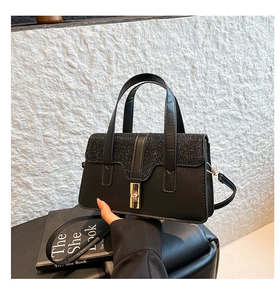 Details einer eleganten schwarzen Handtasche mit glitzernden Pailletten und Goldschloss