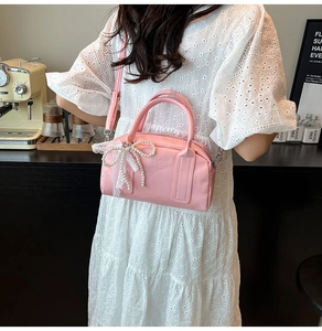 Detail of pink Boston bag with large pearl bow and lace accents on a shoulder strap