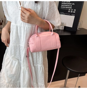 Détail du sac Boston en cuir rose avec texte embossé et bandoulière réglable