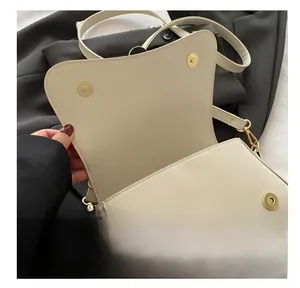 Close-up of beige leather handbag featuring double gold magnetic snap button closures