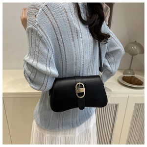 Close-up of a black leather underarm bag featuring a textured golden D-buckle detail