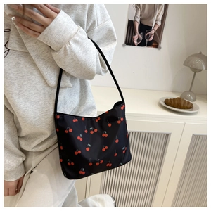 Shoulder bag with red cherry print being worn by a model in a cozy home setting